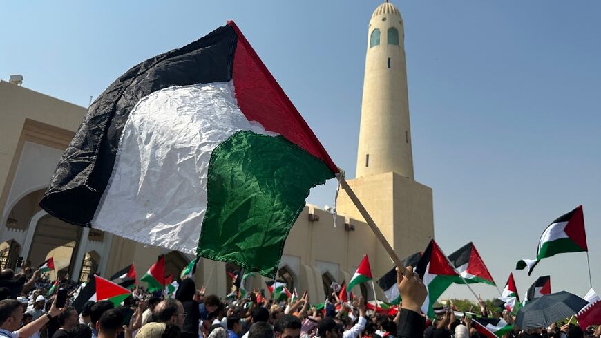 People wave the Palestinian flag during protests in Doha after the outbreak of the Gaza war