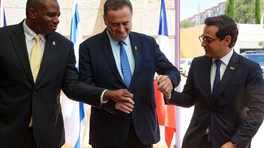 Israel's top diplomat Israel Katz (C) holds hands with his French and British counterparts, Stephane Sejourne (R) and David Lammy, in Jerusalem