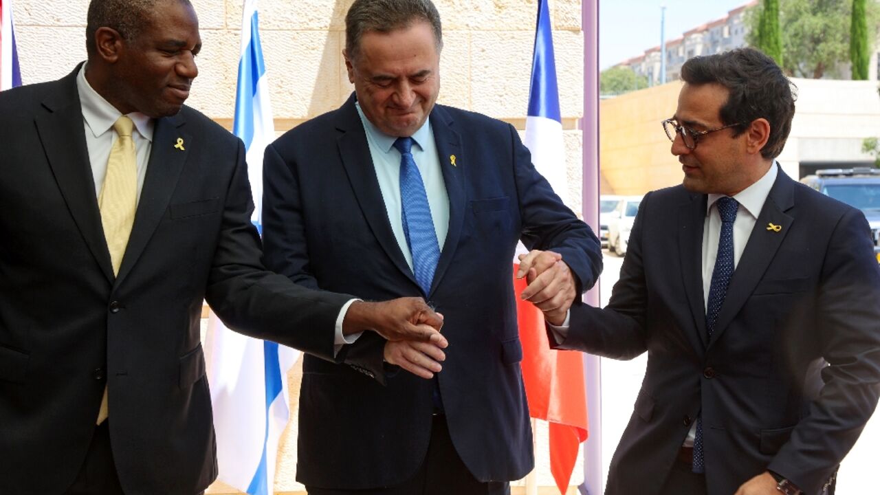 Israel's top diplomat Israel Katz (C) holds hands with his French and British counterparts, Stephane Sejourne (R) and David Lammy, in Jerusalem