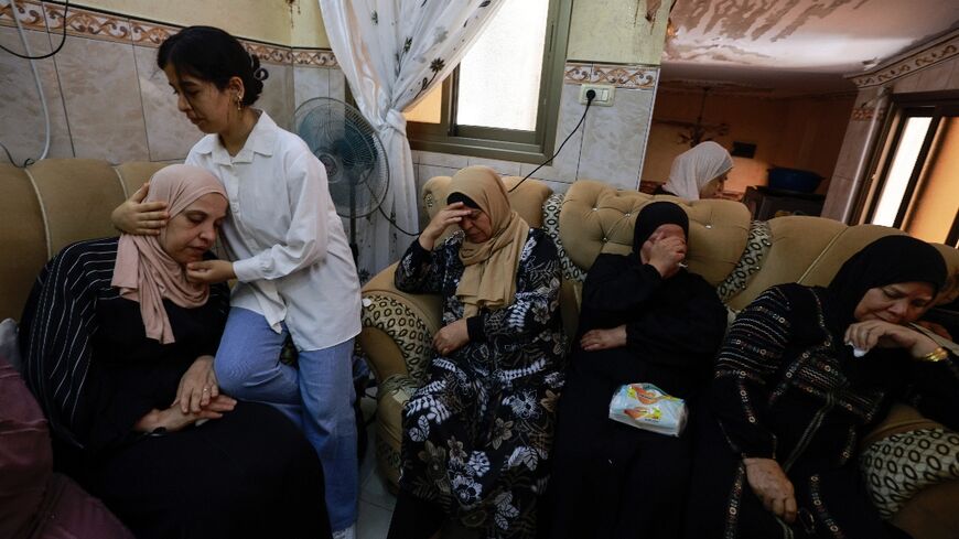 A girl comforts the mother of a Palestinian man killed during an attack by Jewish settlers on the village of Jit in the occupied West Bank