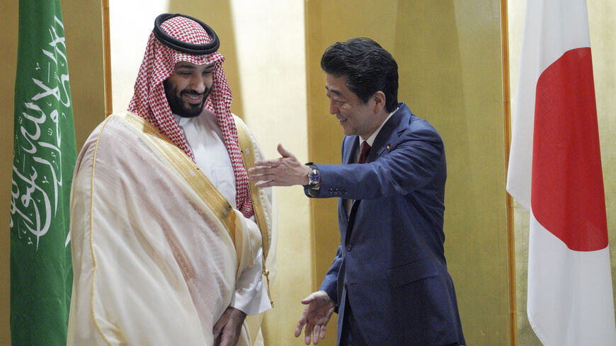 Saudi Arabia's Crown Prince Mohammed bin Salman (L) is escorted by Japanese Prime Minister Shinzo Abe, who was killed on July 8, 2022, during their meeting in Osaka, Japan, June 30, 2019.