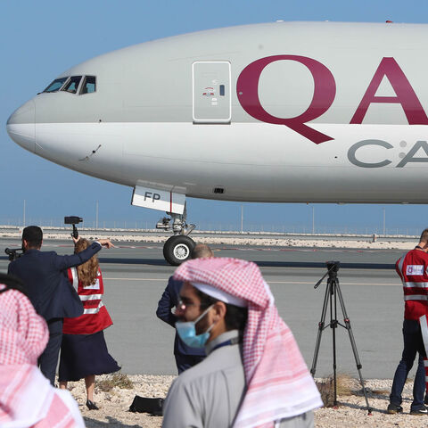 Reporters gather near a Qatar Airways cargo airplane on the tarmac of Hamad International Airport, as the first commercial flight to Saudi Arabia in three and a half years following a Gulf diplomatic thaw prepares for take-off, Doha, Qatar, Jan. 11, 2021. 