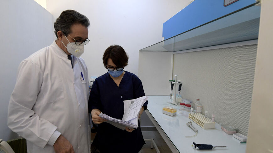 The head of the gynecology department of the in vitro fertilization unit at Aziza Othmana hospital, Fethi Zhiwa (L), speaks in the egg and sperm processing and freezing laboratory with the medical biologist and associate professor in reproductive biology of his service, Khadija Kacem Berejeb, on February 9, 2022 in Tunis. - Under Tunisian law, single women can only freeze their eggs if they are facing medical treatment, such as chemotherapy, "that could affect their ability to procreate". Under the country'