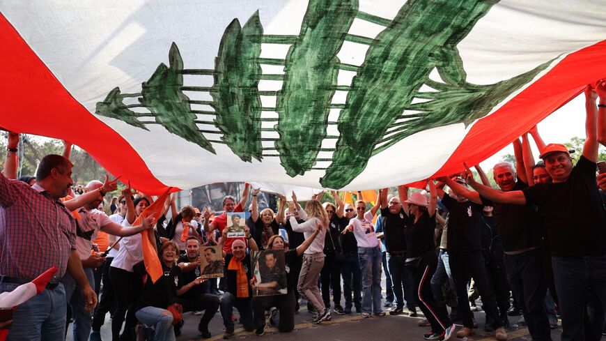 Supporters of Lebanon's President Michel Aoun cheer under a large national flag, as he prepares to leave the presidential palace in Babbda at the end of his mandate, east of the capital Beirut, on October 30, 2022. - Already reeling from three years of economic meltdown, Lebanon faces the prospect of its multi-faceted crisis deepening further when President Michel Aoun's mandate expires. (Photo by anwar amro / AFP) (Photo by ANWAR AMRO/AFP via Getty Images)