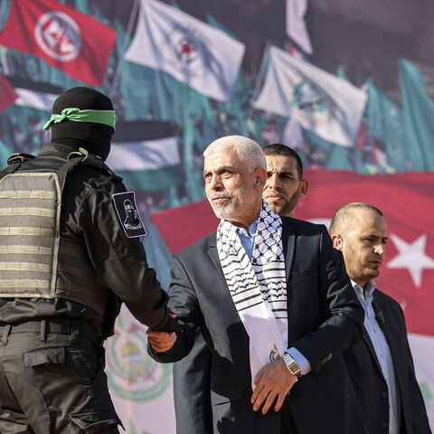 Yahya al-Sinwar (C), Gaza Strip chief of the Palestinian Islamist Hamas movement, shakes hands with a masked fighter of Hamas' Qassam Brigades during a rally marking the 35th anniversary of the group's foundation, in Gaza City on December 14, 2022. Hamas will end talks on securing a prisoner exchange with Israel unless there is progress soon, the militant group's leader in the Gaza Strip said on December 14. Since Israel's 2014 invasion of the Gaza Strip, the Islamist group has held the bodies of Israeli so