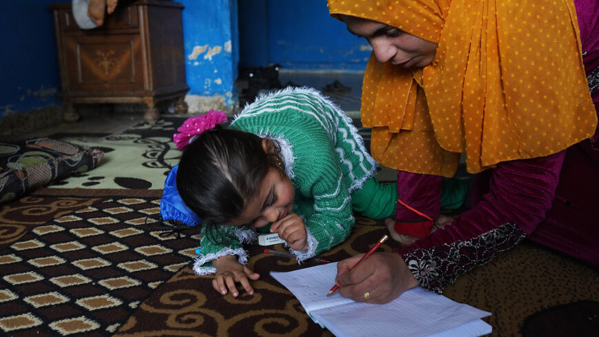 Aisha Mohammed Ali, 25, a mother of five who is a refugee from Aleppo, Syria, teaches the alphabet to one of her daughters, on January 5, 2022 in Tripoli, Lebanon. Tripoli is home to one of the country's largest population of Syrian refugees, 9 out of 10 of whom live in extreme poverty. (Photo by Andreea Campeanu/Getty Images)