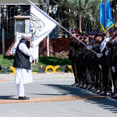 Taliban Interior Minister Sirajuddin Haqqani (C) kisses the Taliban flag as he reviews the newly recruited Afghan security personnel during their graduation ceremony at the police academy in Kabul on October 5, 2023. (Photo by Wakil KOHSAR / AFP) (Photo by WAKIL KOHSAR/AFP via Getty Images)