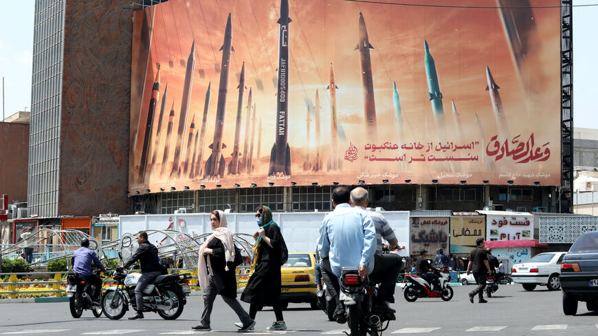 Motorists drive their vehicles past a billboard depicting Iranian missiles in Tehran on April 20, 2024, a day after Iran's state media reported explosions in the central province of Isfahan. 