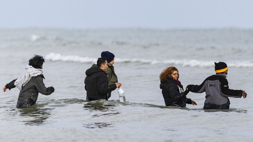 TOPSHOT - Migrants walk in the sea to board a smuggler's boat in an attempt to cross the English Channel, on the beach of Gravelines, near Dunkirk, northern France on April 26, 2024. Five migrants, including a seven-year-old girl, died on April 23, 2024 trying to cross the Channel from France to Britain, local authorities said, just hours after Britain passed a controversial bill to deport asylum seekers to Rwanda. (Photo by Sameer Al-DOUMY / AFP) (Photo by SAMEER AL-DOUMY/AFP via Getty Images)