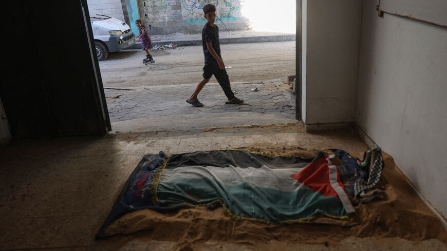 Palestinian children passing by on the street look at the makeshift gravesite of Khaled Abu Obeid at his family's home in Gaza City's Sheikh Radwan neighbourhood on August 7, 2024. Khaled was feeding pigeons on their rooftop when he was killed by a sniper on December 21 amid an Israeli siege of the area, forcing the family and neighbours to dig his grave at home, where it remains, the family said. (Photo by Omar AL-QATTAA / AFP) (Photo by OMAR AL-QATTAA/AFP via Getty Images)