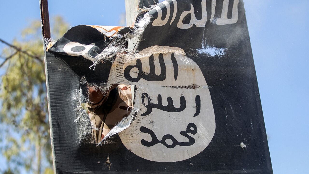 A member of Hashed Al-Shaabi (Popular Mobilization units) removes a sign on a lamp post bearing the logo of the Islamic State (IS) group on August 26, 2017. 