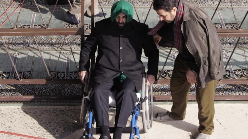 A man helps a veteran of the war between Iraq and Iran during Friday prayers in Tehran  January 5, 2007. REUTERS/Raheb Homavandi (IRAN) - RTR1KWIB